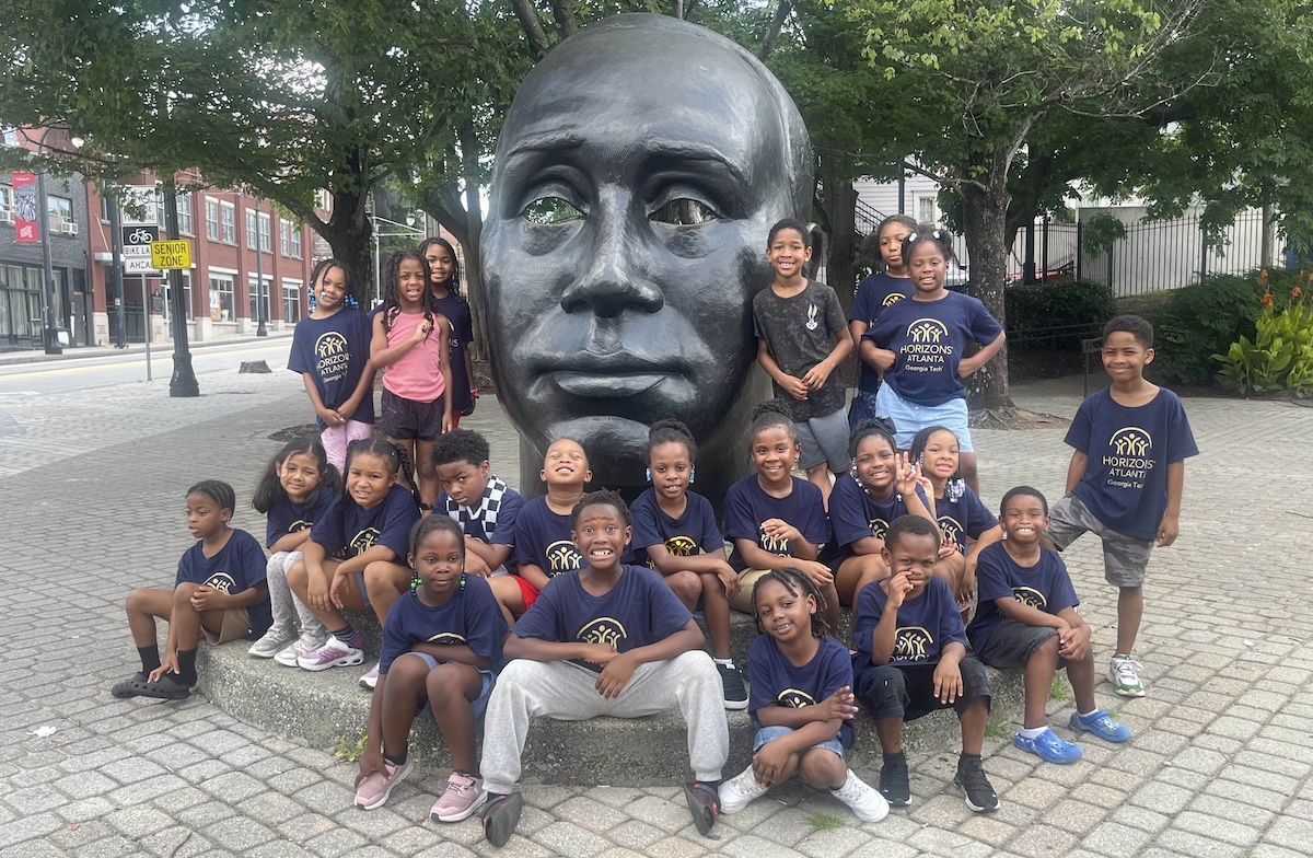 Horizons scholars sit at a statue.